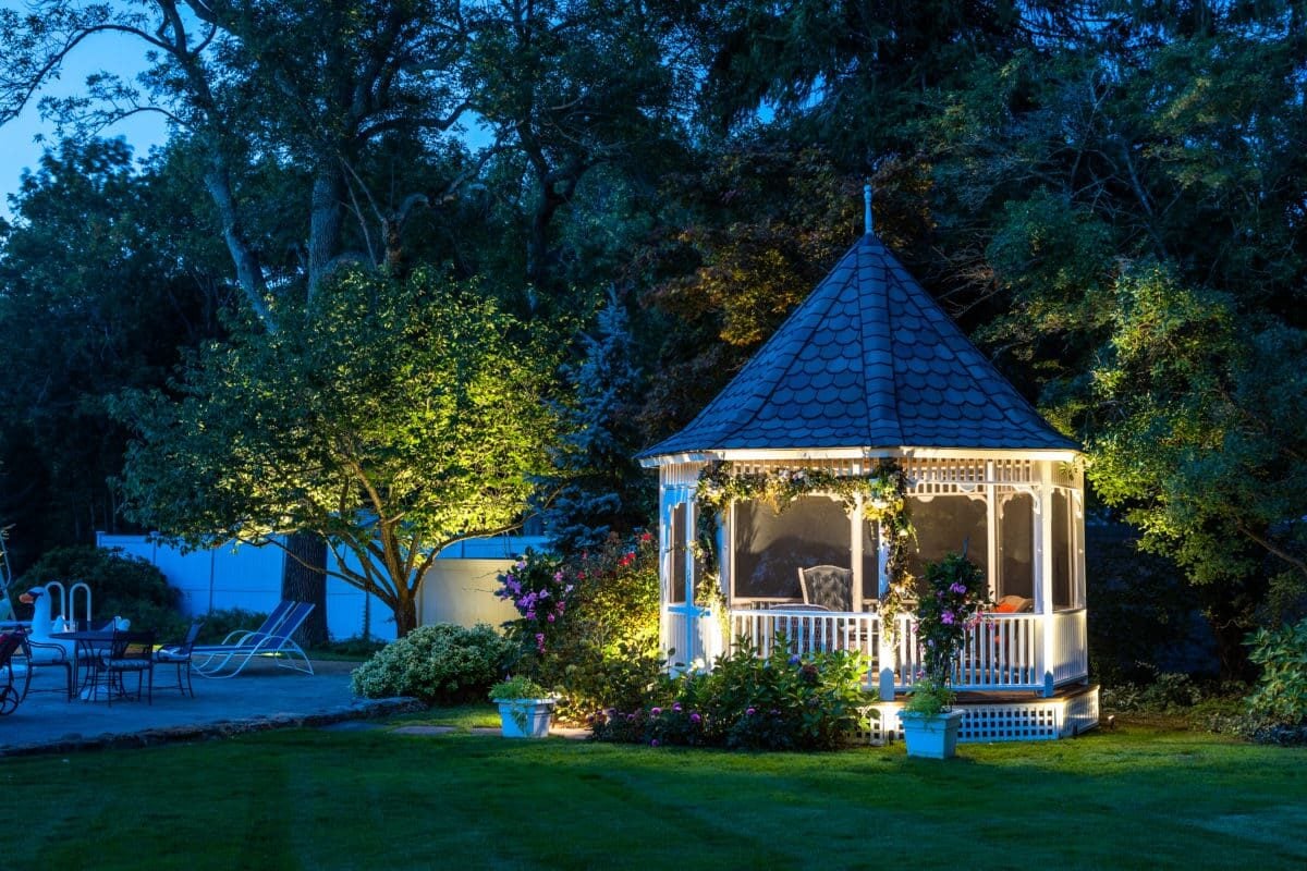 Gazebo and trees illuminated by landscape lighting at dusk